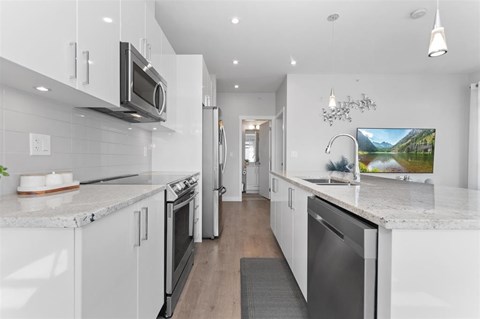A modern kitchen with white cabinets and stainless steel appliances.