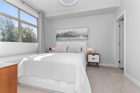 A bedroom with a large bed and a painting on the wall.