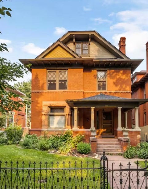 A Victorian style house with a black iron fence in front.