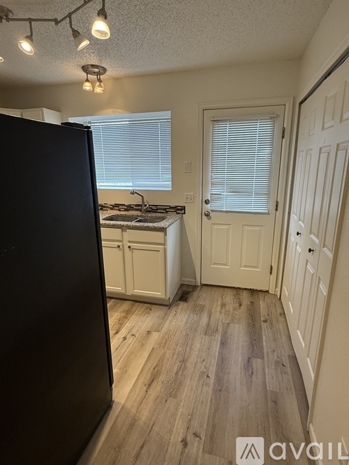 A kitchen with a black refrigerator and wooden floors.