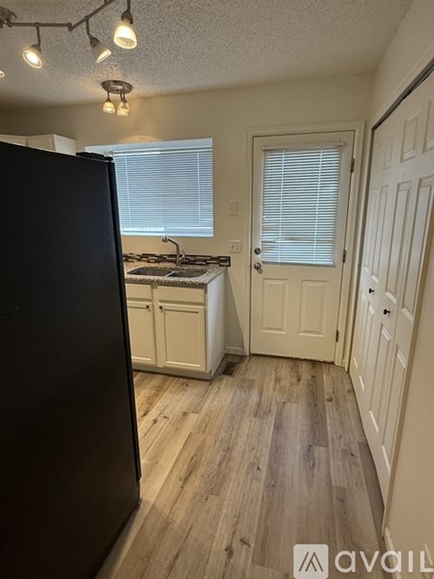 A kitchen with a black refrigerator and wooden floors.