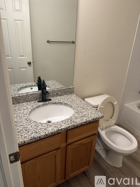 A bathroom with a granite countertop and a white toilet.