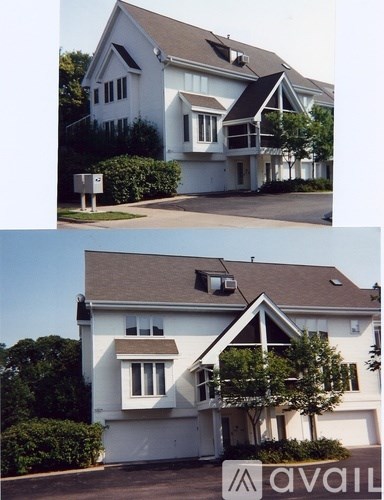 A white house with a brown roof and a tree in front.