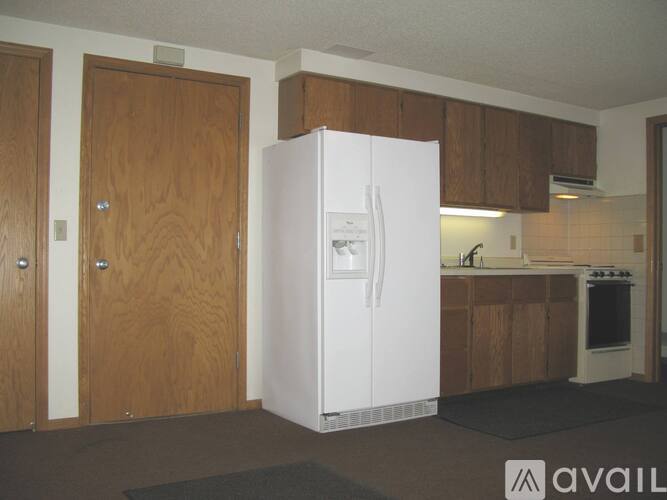 A white refrigerator in a kitchen with wooden cabinets.