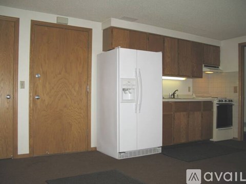 A white refrigerator in a kitchen with wooden cabinets.