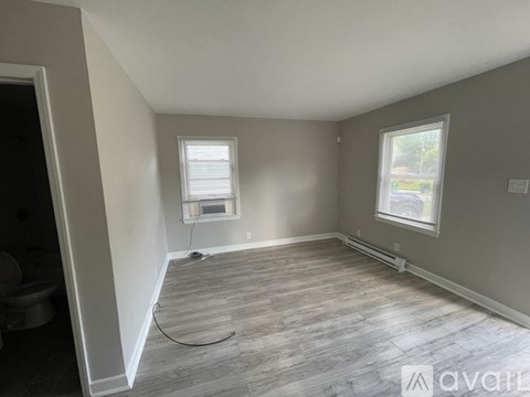 A room with a grey floor and two windows.