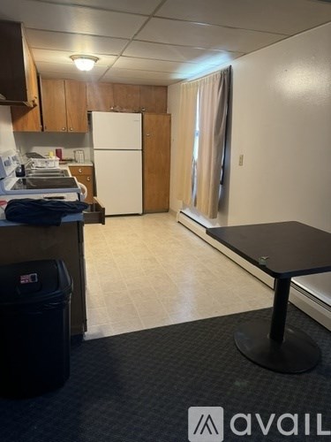 A kitchen area with a fridge, cabinets, and a black table.