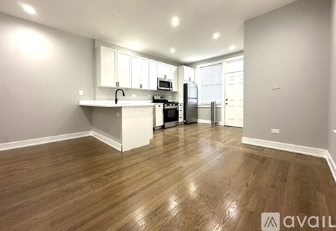 A kitchen with white cabinets and a wooden floor.