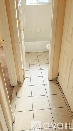 A hallway with white tile flooring and white walls.