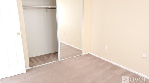 A room with beige walls and carpeted floor with a door open to another room.