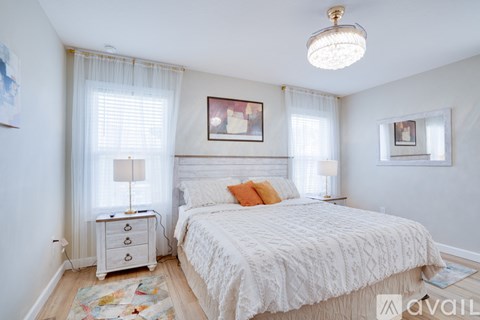 A bedroom with a large bed, a chest of drawers, and a window with curtains.