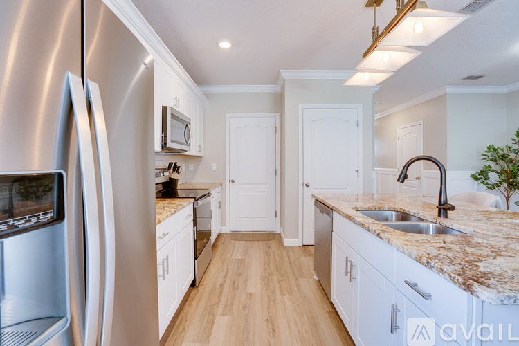 A kitchen with a stainless steel refrigerator and a marble countertop.