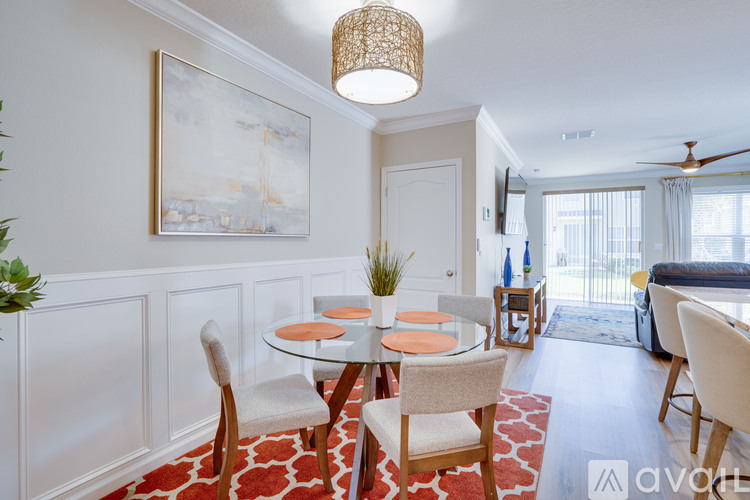 A dining room with a table set for two and a painting on the wall.