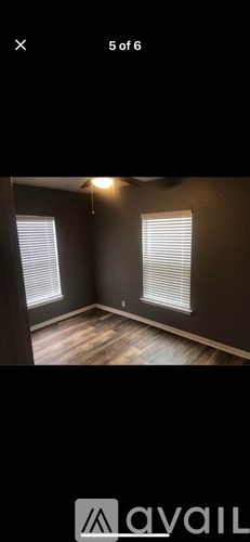 A room with two windows and wooden flooring.