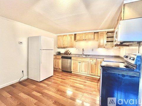 A kitchen with wooden floors and a white refrigerator.