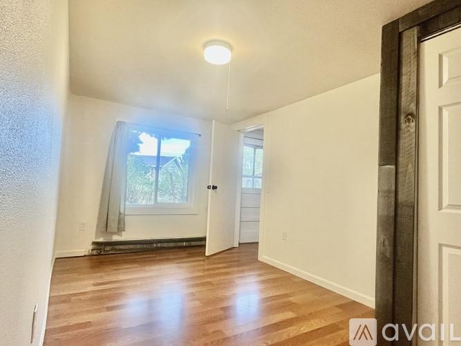A room with wooden floors and a window with a view of trees.