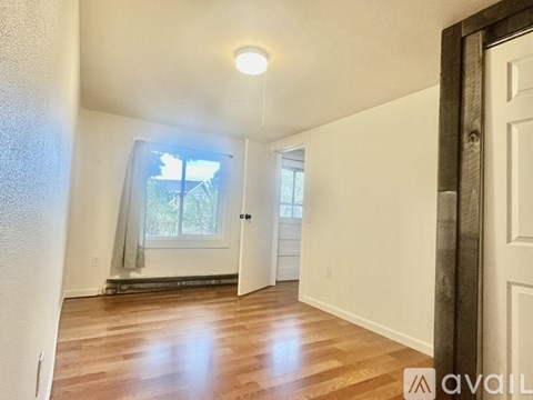 A room with wooden floors and a window with a view of trees.