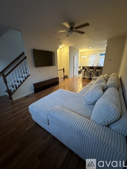 A living room with a white couch and a television mounted on the wall.