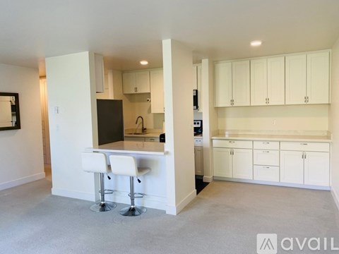 A kitchen with white cabinets and a bar area with stools.