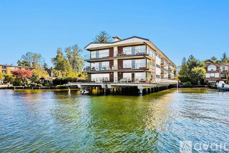 A modern building with a glass balcony overlooking a body of water.
