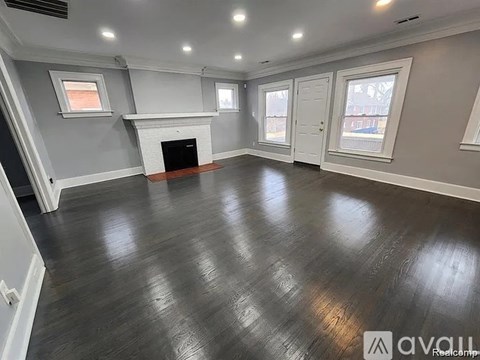 A spacious room with a fireplace and wood flooring.