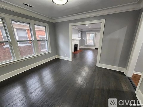 A room with a fireplace and a window overlooking a brick building.