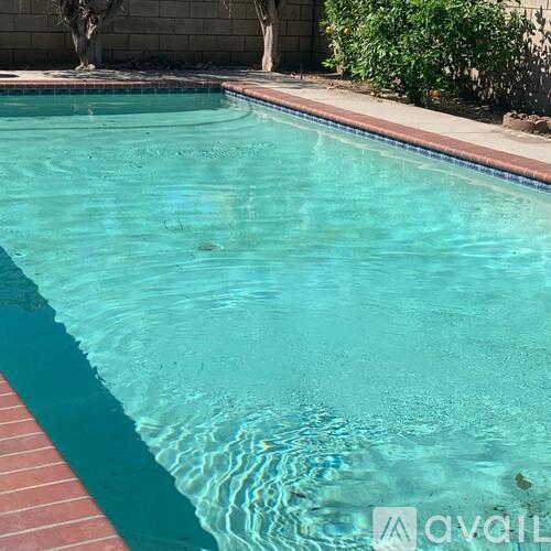 A pool with a red tile border and clear water.