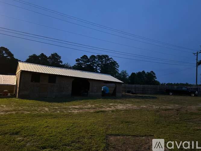 A large building with a metal roof is surrounded by a grassy field.