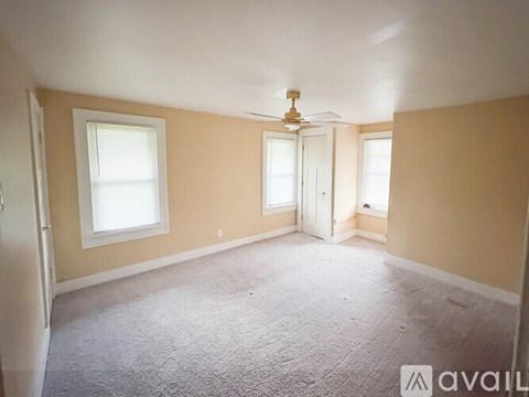 A room with a carpeted floor and a ceiling fan.