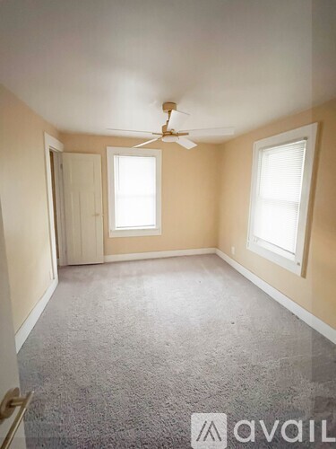 A room with a carpeted floor and a ceiling fan.