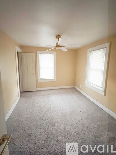 A room with a carpeted floor and a ceiling fan.