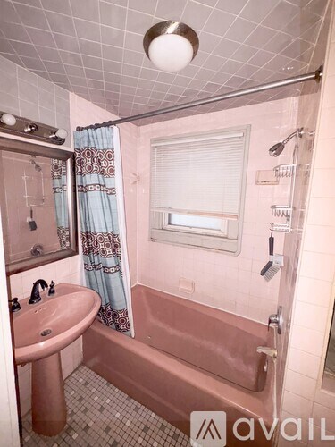 A bathroom with a pink tub and a sink.