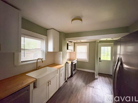 A kitchen with white cabinets and a wooden counter top.