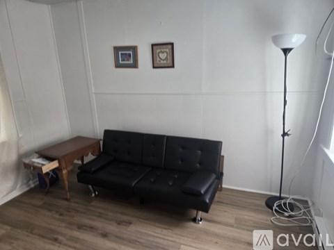 A black sofa with a wooden table and a floor lamp in a room.