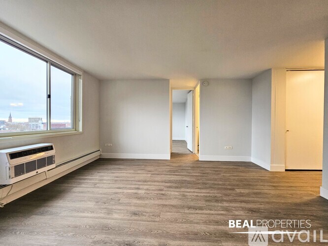 A spacious room with a window overlooking a cityscape is available for rent.