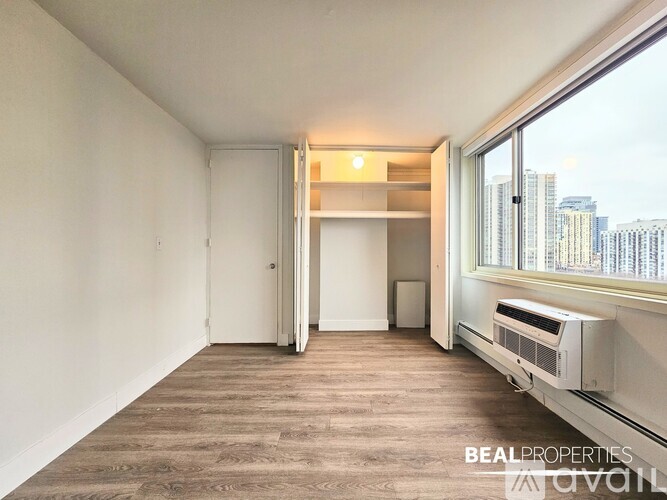 A room with a window overlooking a cityscape and a wall-mounted air conditioning unit.