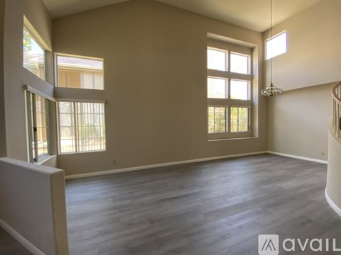 A spacious room with wooden flooring and large windows.