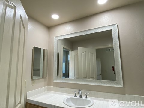 A bathroom with a sink, mirror, and lighting fixture.