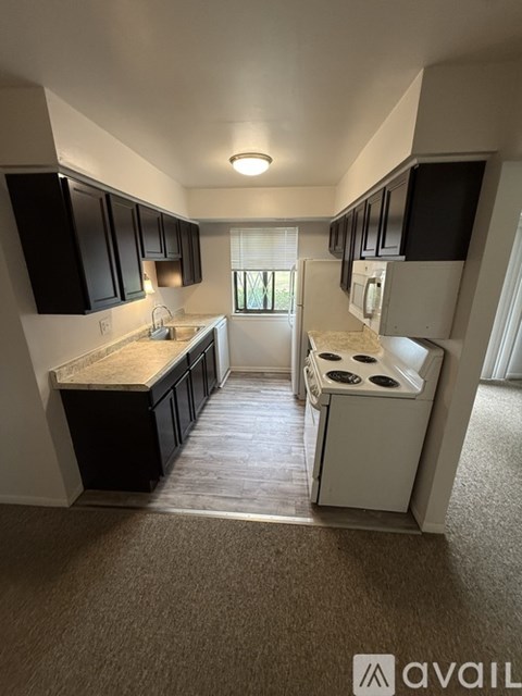 A kitchen with black cabinets and a white stove top oven.