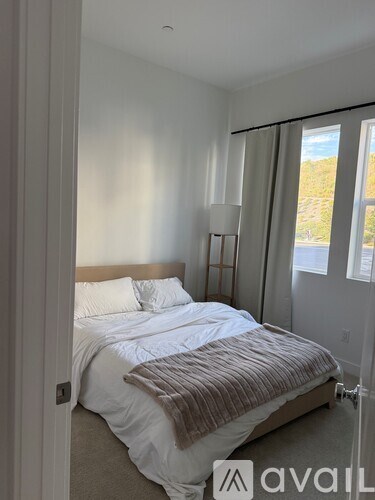 A bedroom with a large bed and a window with curtains.