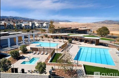 A large outdoor swimming pool surrounded by a grassy area and a building in the background.