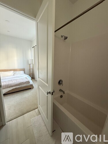 A white bathroom with a bedroom door leading to a bathroom.