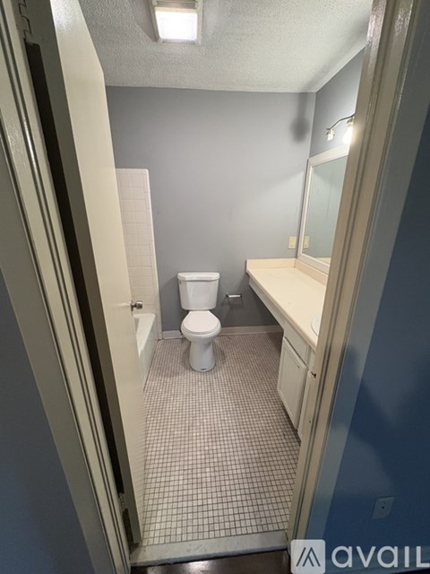 A bathroom with a toilet, sink, and tiled floor.