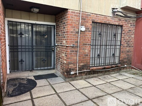 A brick building with a black gate and a red door.