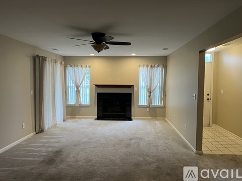 A spacious living room with a fireplace and a ceiling fan.