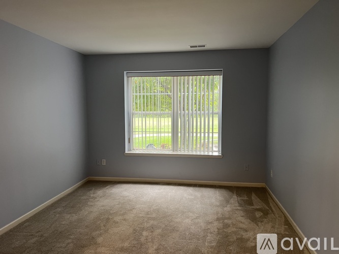 A room with a window and a carpeted floor.