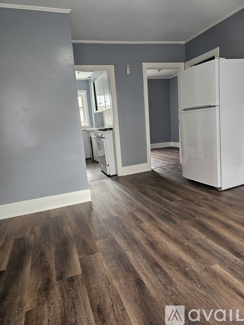 A kitchen with a white refrigerator and wooden floors.
