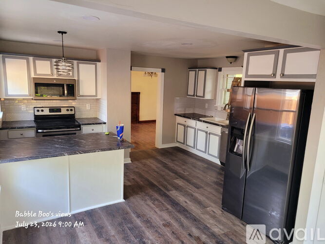 A kitchen with a black refrigerator and white cabinets.