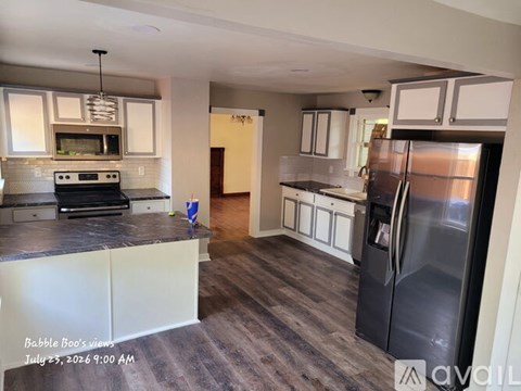 A kitchen with a black refrigerator and white cabinets.