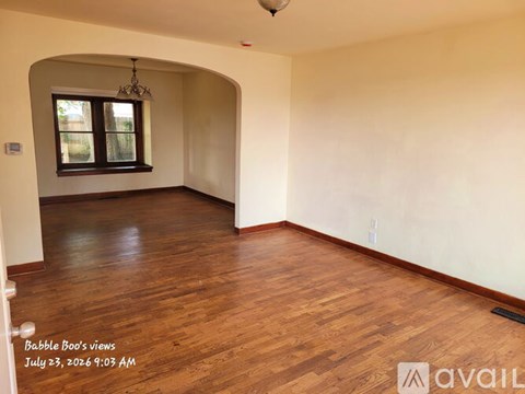 A room with wooden flooring and a window with a chandelier.